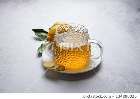 Hot ginger lemon tea in glass cup on a light background with fresh ingredients. Hot ginger lemon tea in glass cup on a light background with fresh ingredients. 134896026