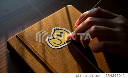 The beginning of the Year of the Rooster. A woman's hand sticks cute chick-patterned stickers on her diary. 134896041