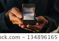 A man's hands offering a ring in a small box for a marriage proposal 134896165