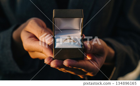 一個男人雙手捧著一個小盒子，裡面裝著一枚戒指，準備求婚。 134896165