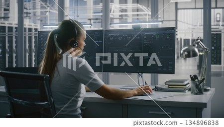 Female Technical Specialist Communicates Via Headset While Tracking Metrics and Graphs Data Female Technical Specialist Communicates Via Headset While Tracking Metrics and Graphs Data 134896838
