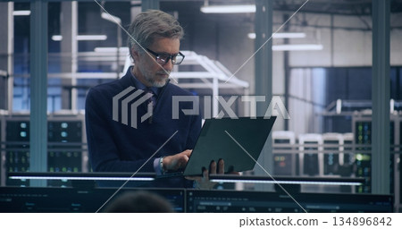 Focused Senior Manager in Formal Business Casual Wear Uses Laptop to Analyze Data Focused Senior Manager in Formal Business Casual Wear Uses Laptop to Analyze Data 134896842