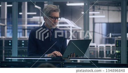 Focused Senior Manager in Formal Business Casual Wear Uses Laptop to Analyze Data Focused Senior Manager in Formal Business Casual Wear Uses Laptop to Analyze Data 134896848