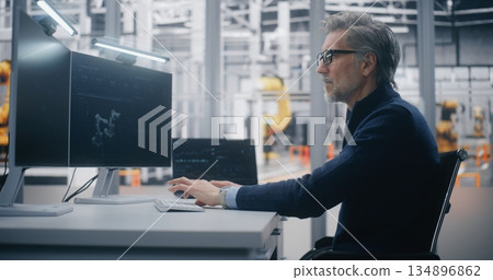 Focused Male Professional Programs Robotic Equipment While Tracking Operational Metrics 134896862