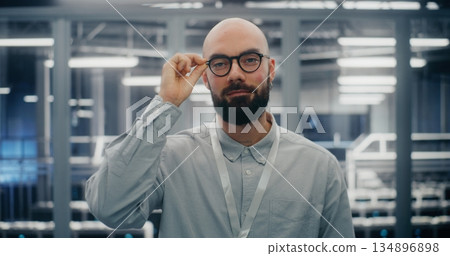 Bearded Male IT Engineer With Glasses, Smiling Confidently While Adjusting Eyewear 134896898