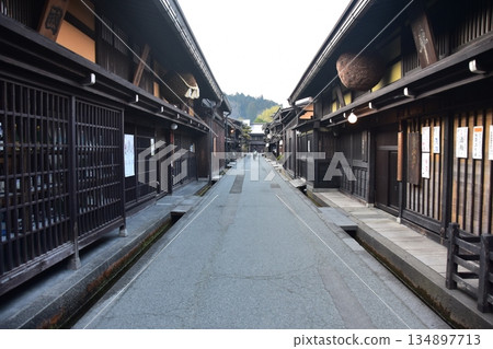 Old townscape of Takayama City, Gifu Prefecture, Japan. A sake shop decorated with cedar balls and an old house with a sense of history. Morning scene during the Takayama Spring Festival. Old townscape of Takayama City, Gifu Prefecture, Japan. A sake shop decorated with cedar balls and an old house with a sense of history. Morning scene during the Takayama Spring Festival. 134897713