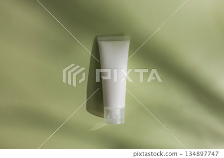 Minimal skincare mockup with blank cosmetic tube on soft green background, styled with natural shadows for clean beauty branding, organic cosmetics and modern packaging design. 134897747