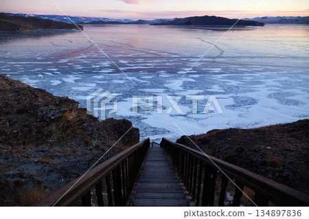 View of frozen Lake Baikal from wooden stairs during sunset in winter 134897836