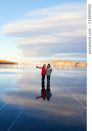 A happy mother and daughter stand on the clear ice of frozen Lake Baikal at sunset A happy mother and daughter stand on the clear ice of frozen Lake Baikal at sunset 134898008