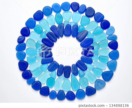 An artistic arrangement of blue sea glass pieces is shaped into a perfect circular mosaic pattern. An artistic arrangement of blue sea glass pieces is shaped into a perfect circular mosaic pattern. 134898136