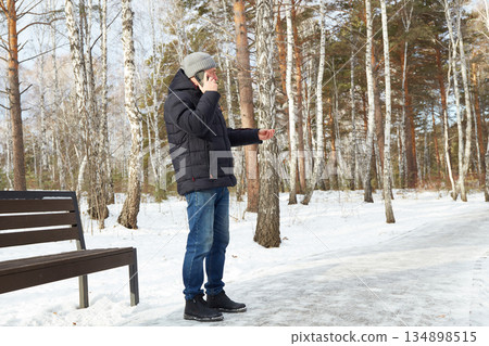 A man talks on the phone while walking in a snowy winter park 134898515