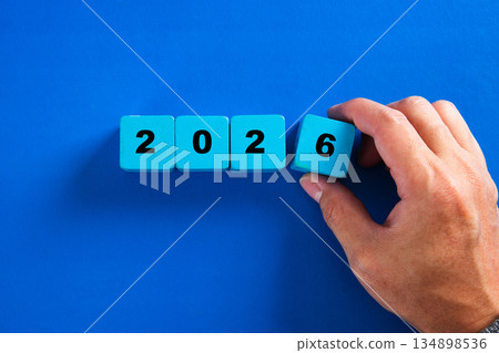 Hand placing blue cube forming year 2026 concept 134898536