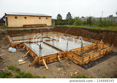 A concrete foundation is being poured on the construction site. Wooden formwork is used. 134898545