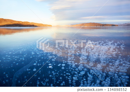 Frozen Lake Baikal on a winter day. Transparent smooth ice with methane bubbles. Frozen Lake Baikal on a winter day. Transparent smooth ice with methane bubbles. 134898552
