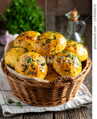 A basket of pampushky garlic bread rolls is brushed with oil and sprinkled with fresh herbs. A basket of pampushky garlic bread rolls is brushed with oil and sprinkled with fresh herbs. 134898632