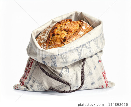 A decorative, patterned linen bread bag is tied loosely, partially revealing a crusty, homemade, round loaf. A decorative, patterned linen bread bag is tied loosely, partially revealing a crusty, homemade, round loaf. 134898636