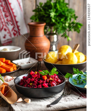 A festive table is set with Ukrainian vinaigrette beet salad, potatoes, carrots, and pickles. A festive table is set with Ukrainian vinaigrette beet salad, potatoes, carrots, and pickles. 134898637