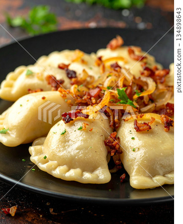 A plate of varenyky dumplings is filled with potatoes and served with fried onions and crispy bacon bits. A plate of varenyky dumplings is filled with potatoes and served with fried onions and crispy bacon bits. 134898643