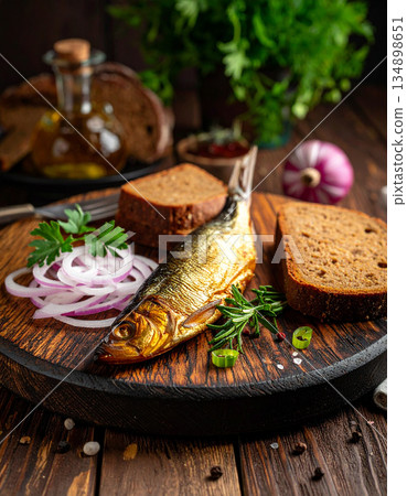 A wooden board displays Ukrainian smoked fish, rye bread, and pickled onions for a rustic appetizer. A wooden board displays Ukrainian smoked fish, rye bread, and pickled onions for a rustic appetizer. 134898651