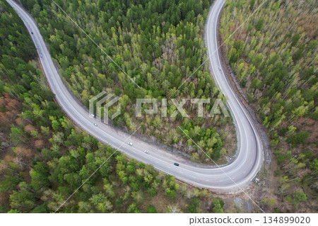Aerial view of the serpentine highway. Cars drive on a road through the spring forest 134899020