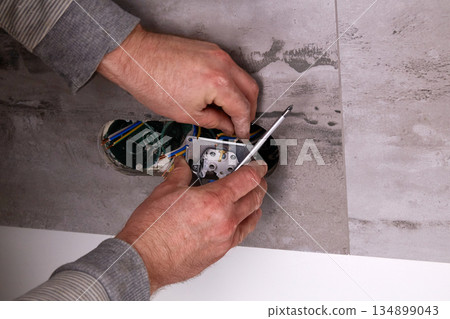 Electrician installing electrical outlets in a wall made of porcelain tiles. Electrician installing electrical outlets in a wall made of porcelain tiles. 134899043