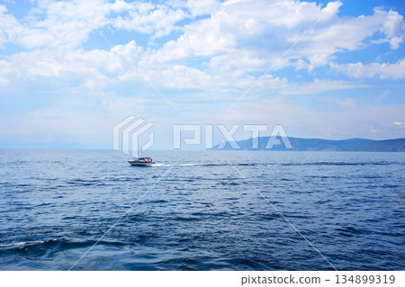 View of a boat in motion on water. Lake Baikal on a summer day. Listvyanka village. View of a boat in motion on water. Lake Baikal on a summer day. Listvyanka village. 134899319