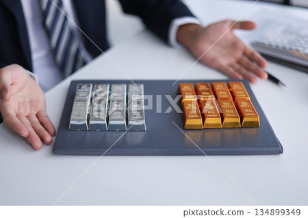 Gold and silver bars on the table. Businessman investing in precious metals to diversify portfolios hedge against inflation and currency depreciation. Gold and silver bars on the table. Businessman investing in precious metals to diversify portfolios hedge against inflation and currency depreciation. 134899349