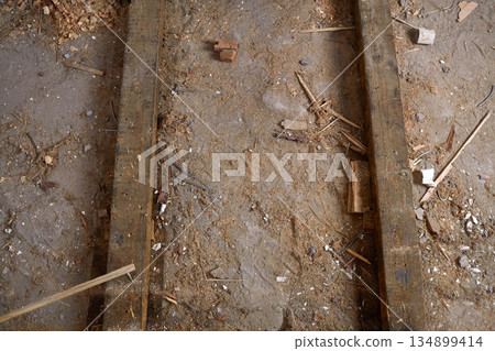 Dusty wooden beams on a concrete floor with debris, sawdust. 134899414