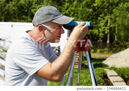 A construction worker checks the height level of the brickwork using a measuring tool on the construction site. A construction worker checks the height level of the brickwork using a measuring tool on the construction site. 134899421