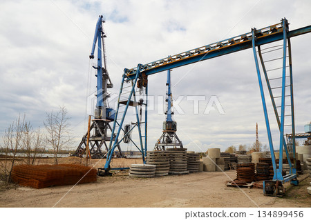Industrial production of reinforced concrete products. Cranes and equipment on the construction site Industrial production of reinforced concrete products. Cranes and equipment on the construction site 134899456