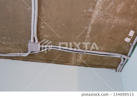 The electrical wires in the protective corrugated cable tube and the junction box are neatly laid on the ceiling 134899513