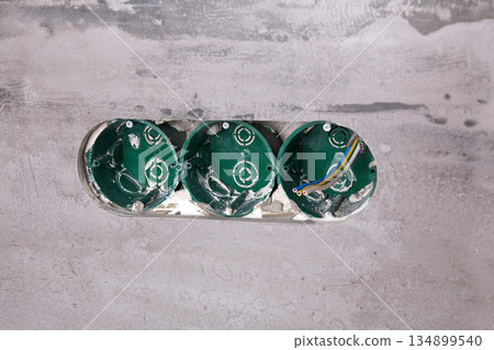 Three electrical boxes for conduits are built into the wall. Work on installing electrical outlets Three electrical boxes for conduits are built into the wall. Work on installing electrical outlets 134899540