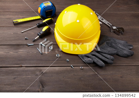 Happy labor day concept. Construction tools, yellow helmet on dark wooden background Happy labor day concept. Construction tools, yellow helmet on dark wooden background 134899542