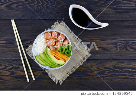 Hawaiian salmon fish poke bowl with rice, avocado, cucumber, carrot, soy sauce 134899543