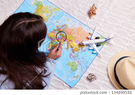The girl explores the world map with a magnifying glass. The girl explores the world map with a magnifying glass. 134899588