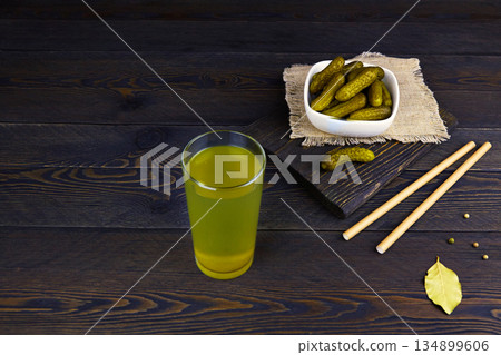 Cucumber pickle or pickle juice in glass, a bowl with pickled gherkins 134899606