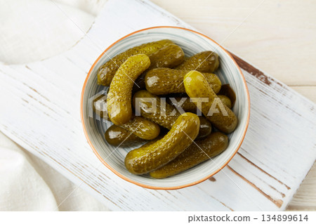 Marinated cucumbers in a bowl on a light wooden background. 134899614