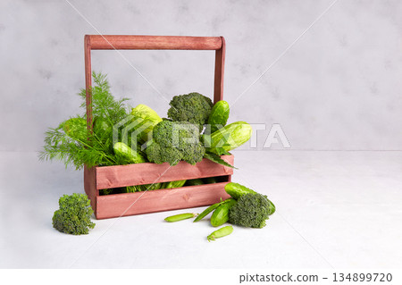 Green vegetables in a wooden box on a gray background. 134899720
