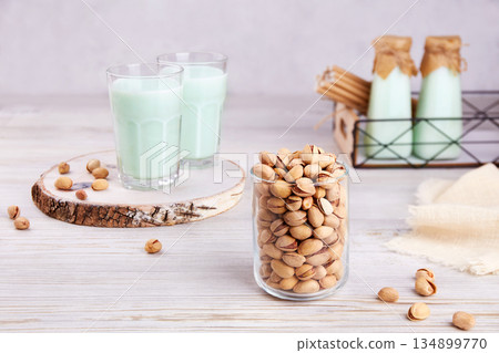 Pistachio milk in glasses and bottles, nuts in jar. 134899770