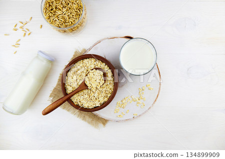Oatmeal milk in a glass and a bottle, oatmeal flakes in a ceramic bowl Oatmeal milk in a glass and a bottle, oatmeal flakes in a ceramic bowl 134899909