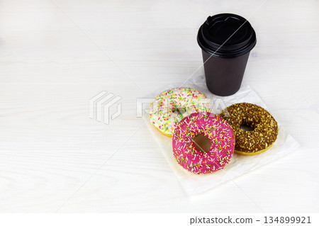 Three colorful glaze donuts with sprinkles and takeaway coffee cup 134899921