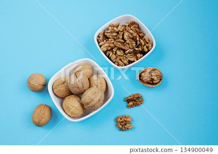 Walnut kernels in a bowls on a blue background. 134900049