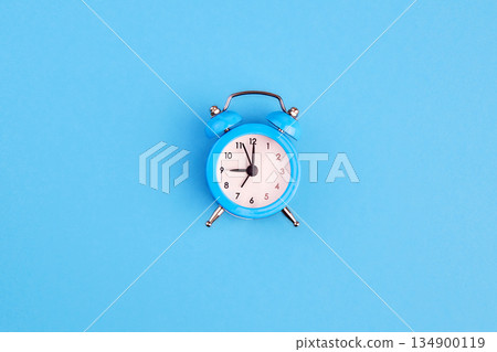 Classic alarm clock on blue background. Top view, copy space. 134900119