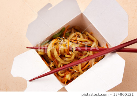 Delicious noodles with colorful vegetables are neatly packed in a white takeout box. Delicious noodles with colorful vegetables are neatly packed in a white takeout box. 134900121