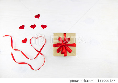 Gift box in craft paper packaging with red ribbon and heart-shaped ribbon 134900127