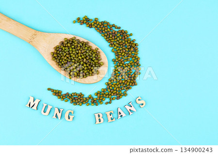 Mung beans in wooden spoon on a green background. Mung beans in wooden spoon on a green background. 134900243