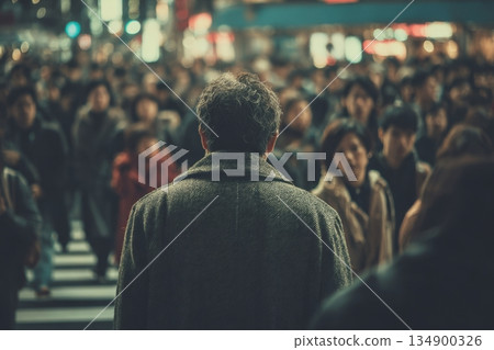 Man stands facing a crowd at a crosswalk in a city. The scene shows many people moving in different directions 134900326
