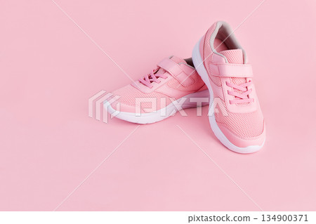 A pair of pink sneakers on a pink background. Women's sports shoes close-up. A pair of pink sneakers on a pink background. Women's sports shoes close-up. 134900371