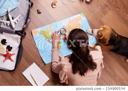 A girl with her dog is exploring the political map, planning a vacation. A girl with her dog is exploring the political map, planning a vacation. 134900534