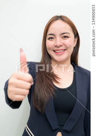 Portrait of a young Asian businesswoman against white background showing thumbs up approval gesture Portrait of a young Asian businesswoman against white background showing thumbs up approval gesture 134900855